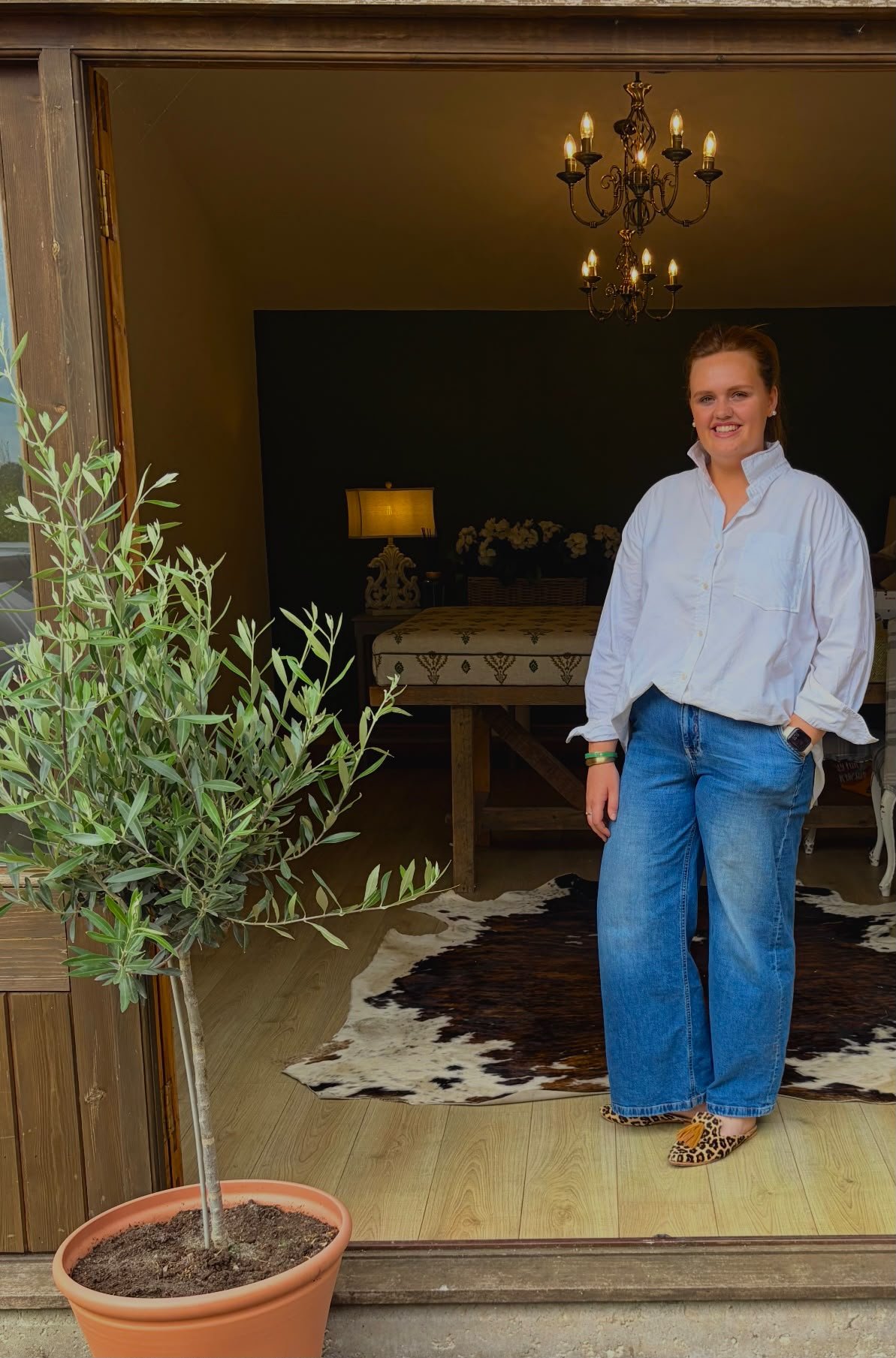 Harriet standing by an olive tree at the entrance to a styled room