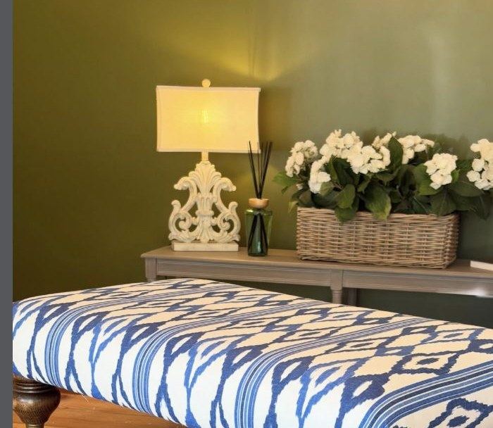 Styled living room with olive green wall, upholstered bench and fresh flowers