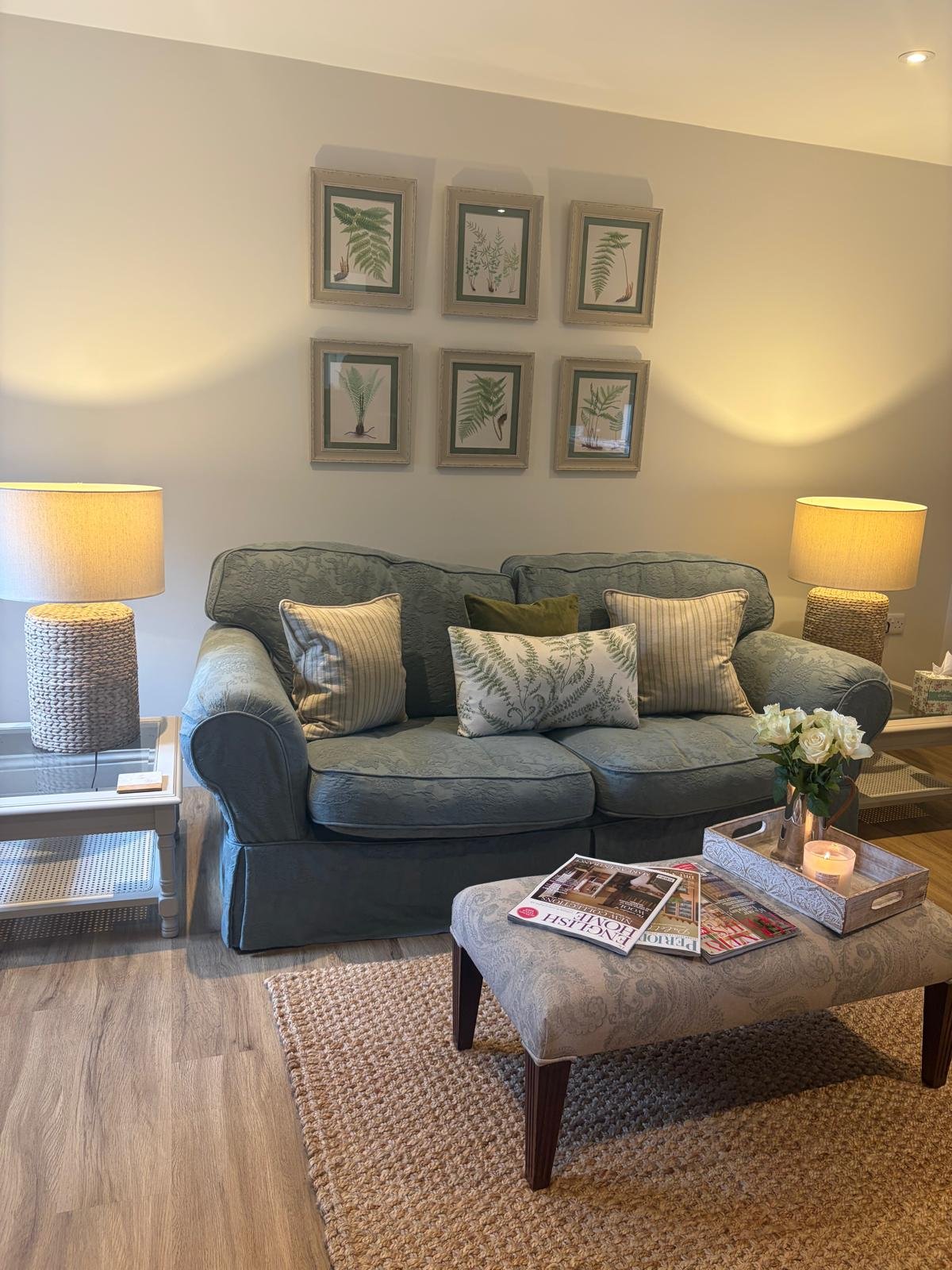 Styled sage green sofa with fern cushions and botanical gallery wall